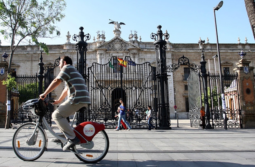 Joven en bicicleta por la puerta del Rectorado de la US